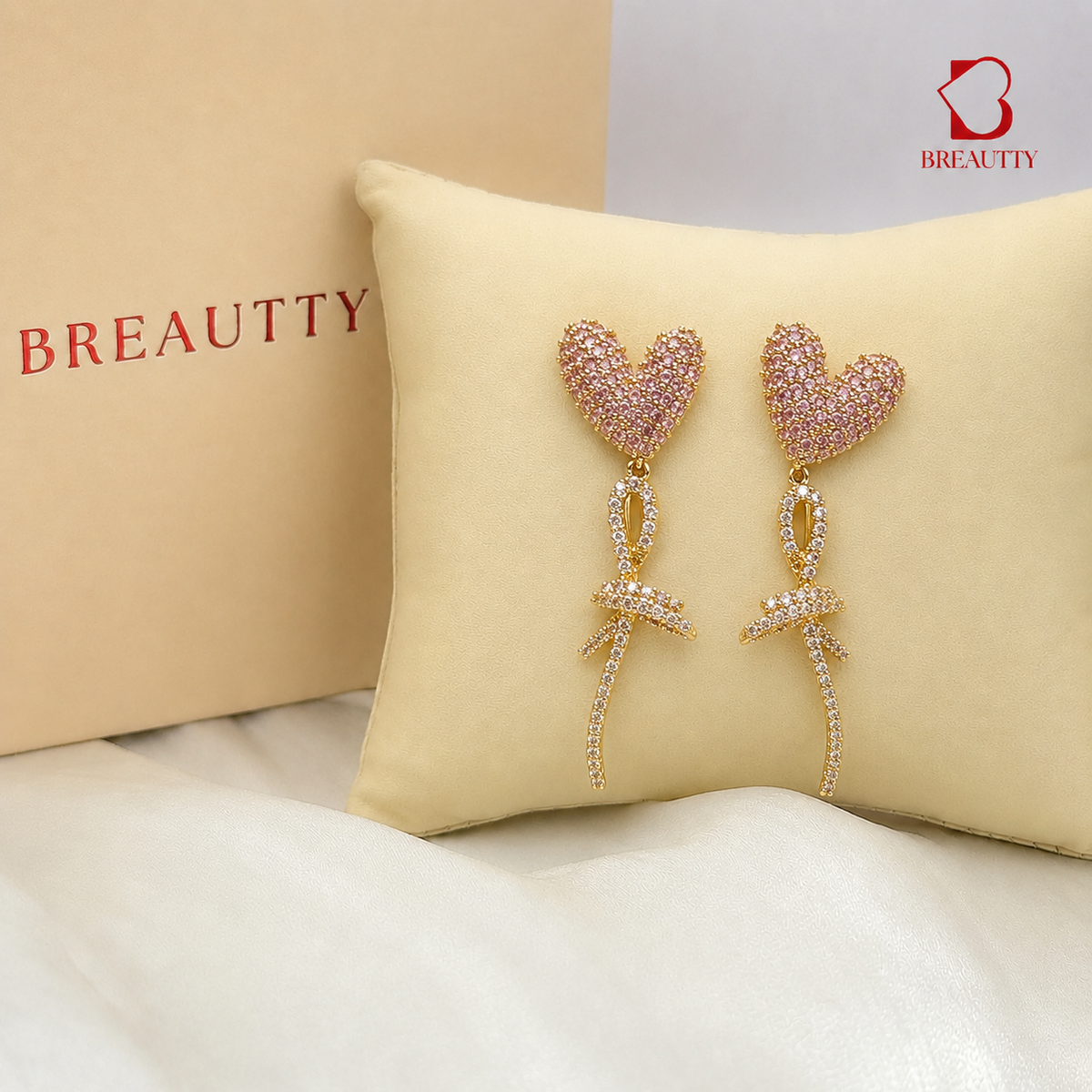Heart-shaped earrings on a cushion with Breautty branding in the background