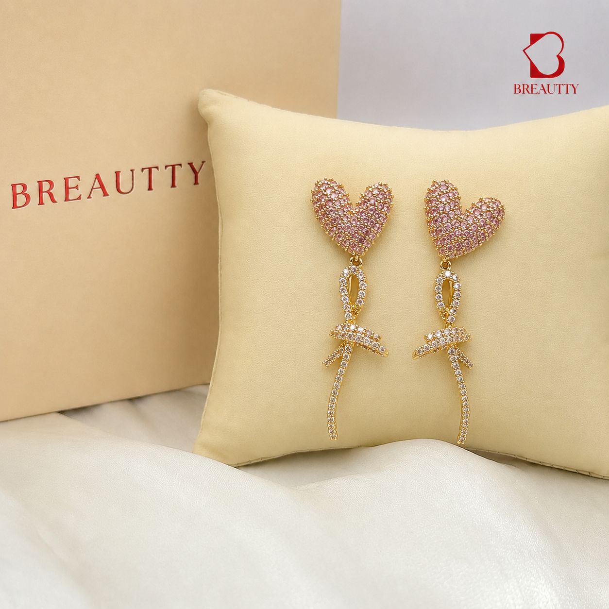 Heart-shaped earrings on a cushion with Breautty branding in the background